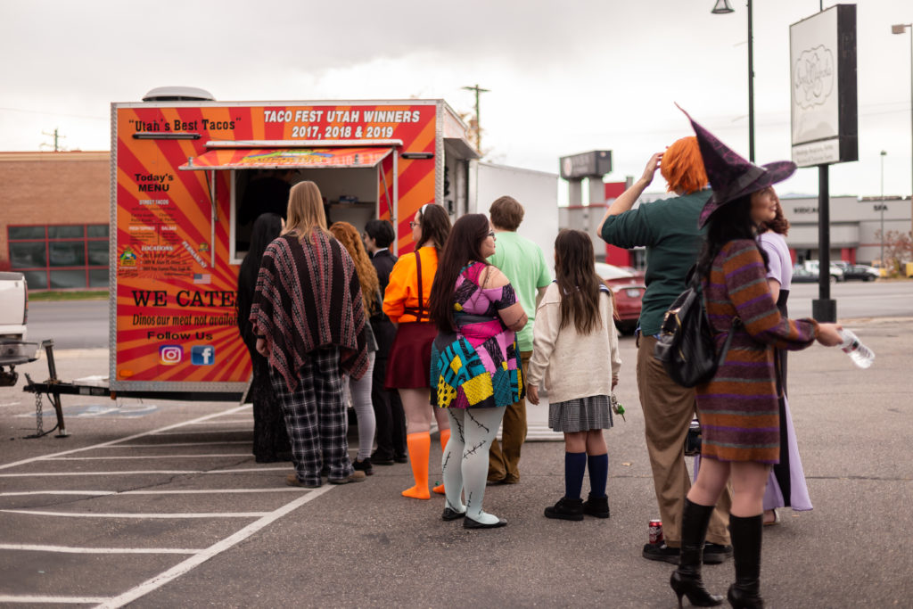 Wedding guests dressed in Halloween costumes waiting in line at a taco truck