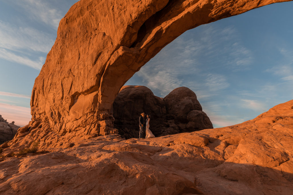 Bride and groom dancing under arch in Arches National Park in Moab, Utah