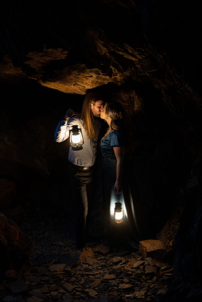 Couple standing in cave kissing holding lanterns in Big Cottonwood Canyon in Salt Lake City, Utah