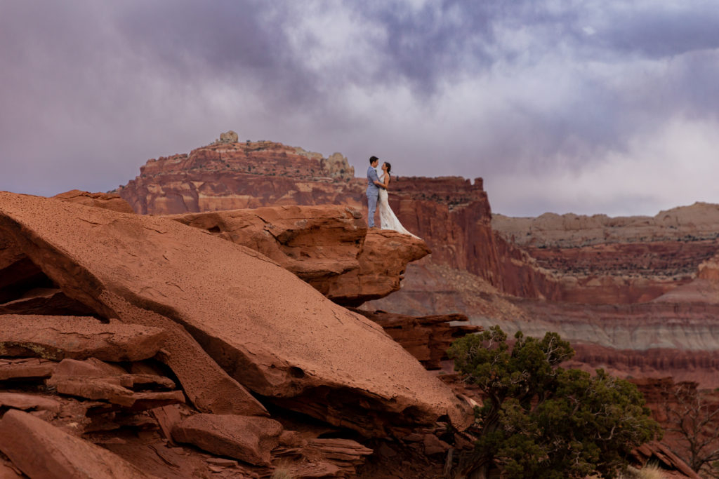 Bride and groom embracing each other on a cliffside in Capitol Reef National Park