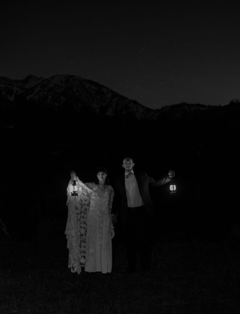 Mountain Elopement Locations Near Salt Lake  - bride and groom holding lanterns at night standing in front of the mountains under the stars