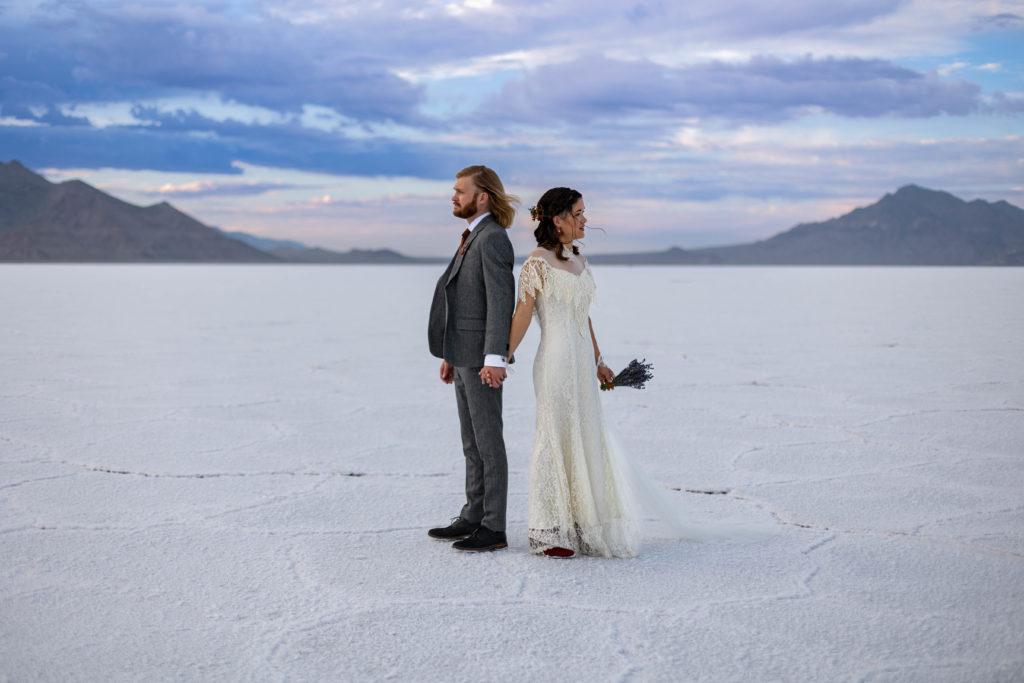 Bonneville Salt Flats Utah Wedding Photos with bride and groom back to back holding hands waiting for their first look