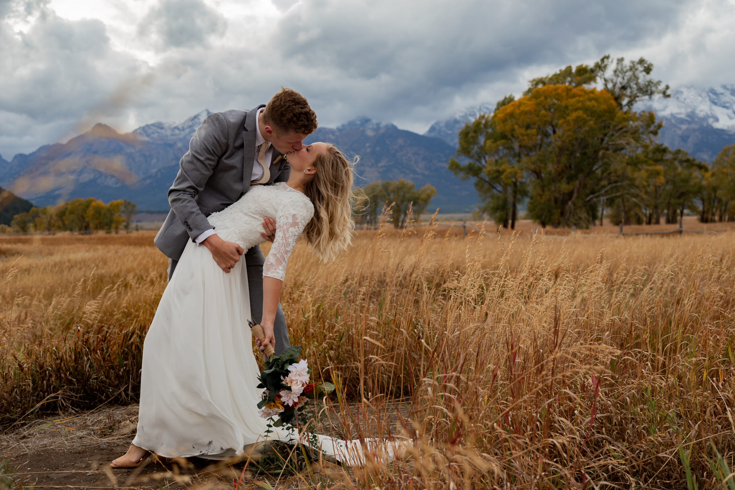 Fall Elopement in Grand Teton National Park in Jackson Hole, Wyoming. Groom is dipping bride and they are kissing while the wind is blowing through the bride's hair.
