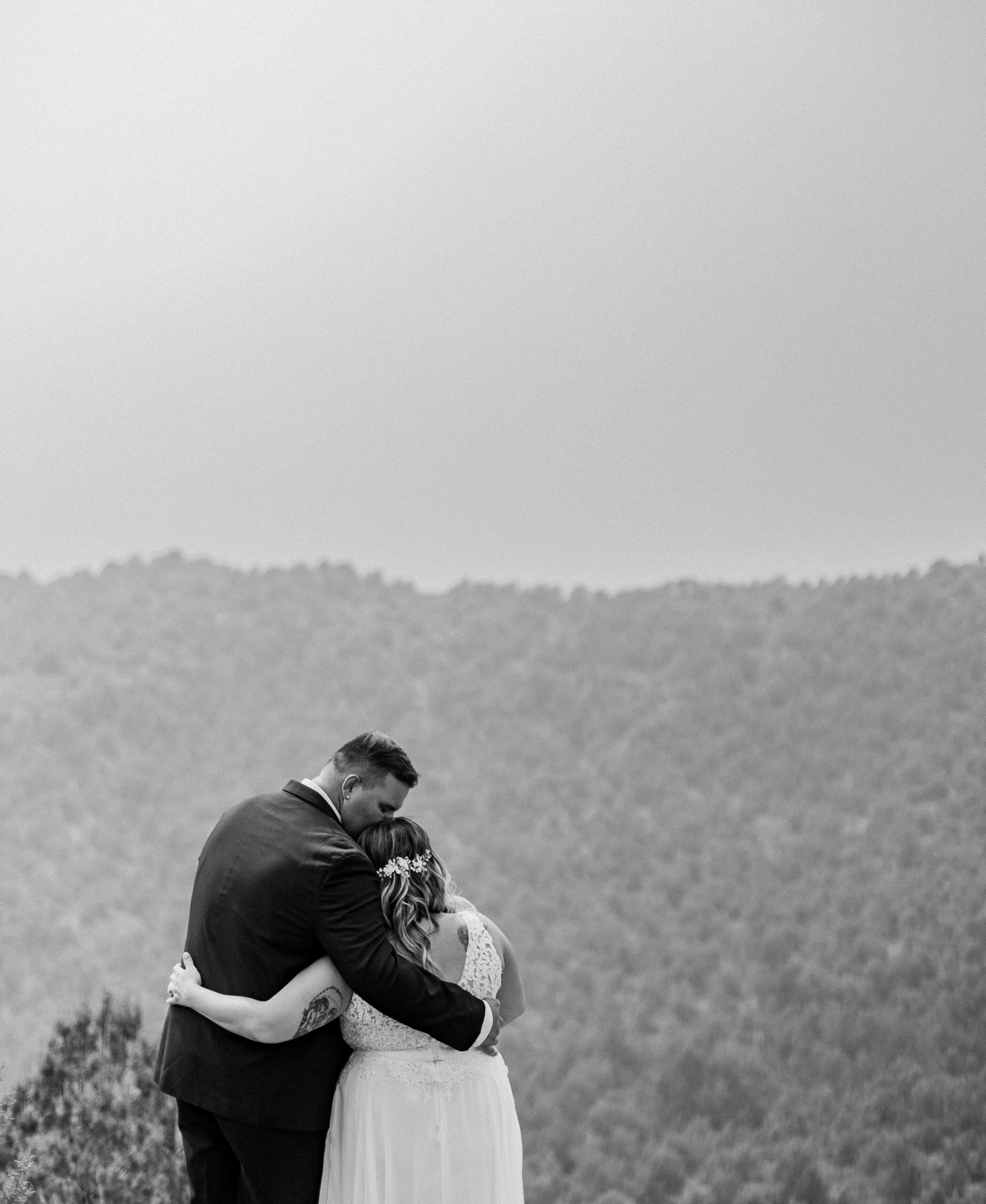 Black and white photos of bride and groom facing away from the camera and embracing each other in a side hug while the groom kisses the top of the bride's head in Zion National Park in Utah.