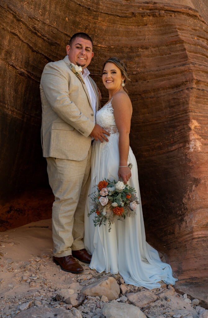 Bride and groom embracing each other while smiling at the camera in a slot canyon in Zion National Park in Utah