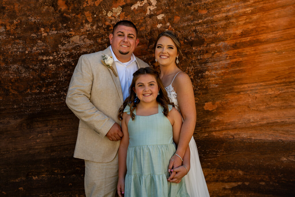 Bride and groom with their daughter in a red rock slot canyon in Zion National Park in Utah