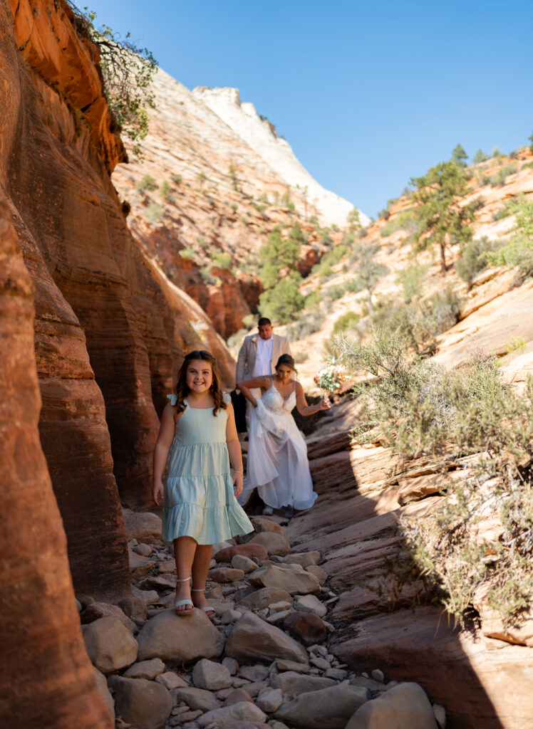 Bride and groom with their daughter in a red rock slot canyon in Zion National Park in Utah