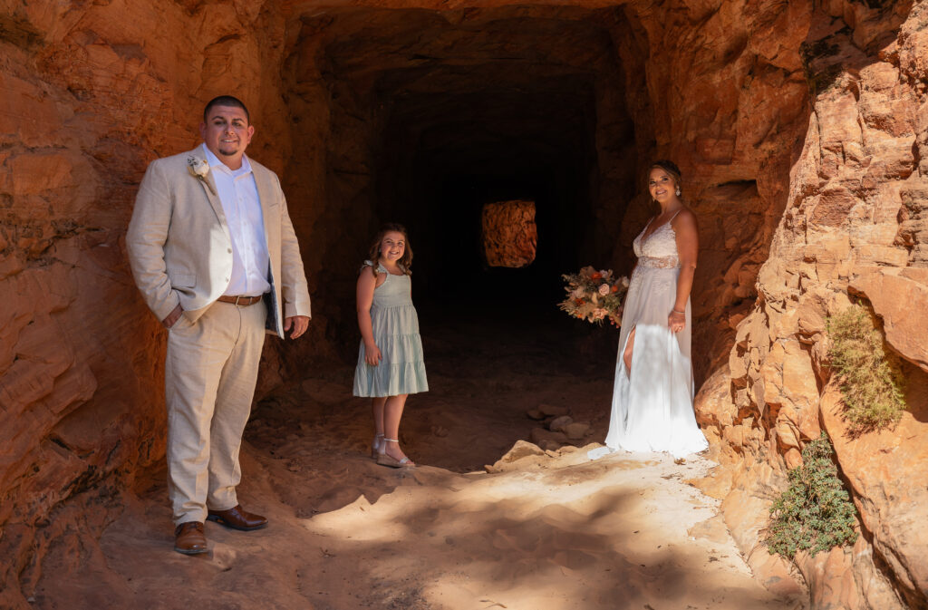Bride and groom with their daughter in a red rock tunnel in Zion National Park in Utah