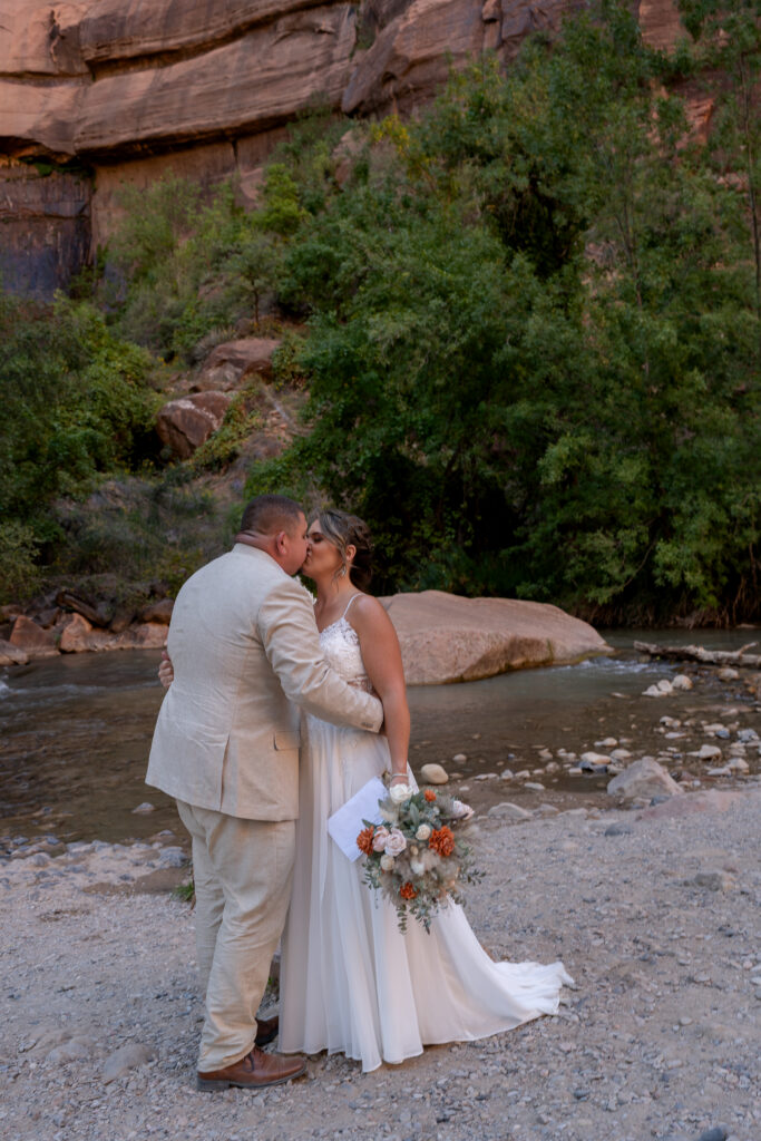 Bride and groom kissing at the Temple of Sinawava in Zion National Park in Utah