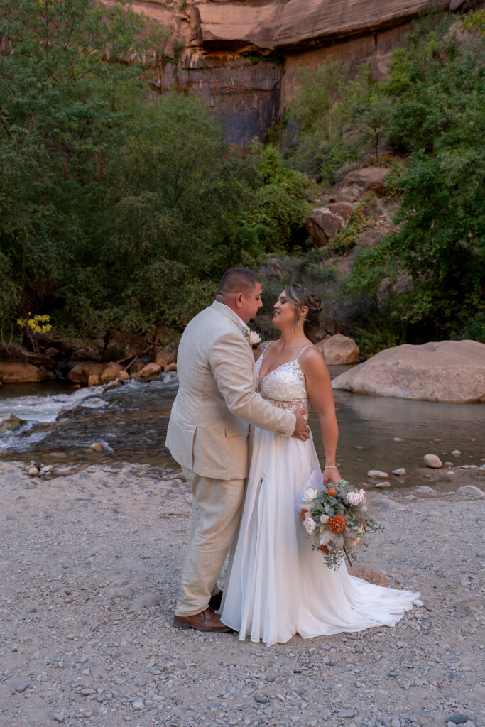 Bride and groom embracing each other at the Temple of Sinawava in Zion National Park in Utah