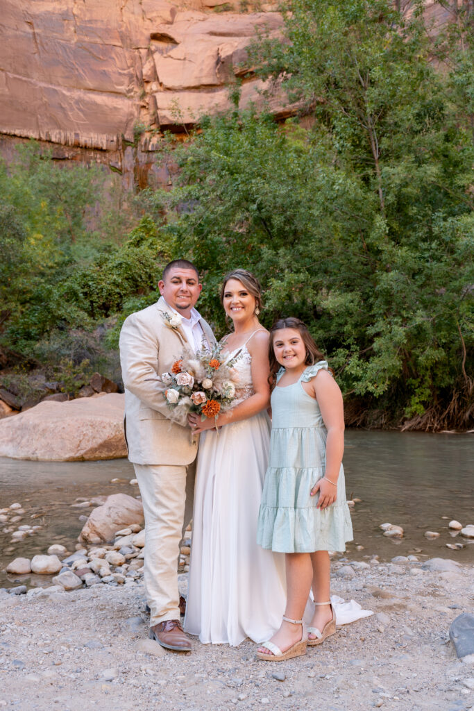 Bride and groom with daughter at the Temple of Sinawava in Zion National Park in Utah