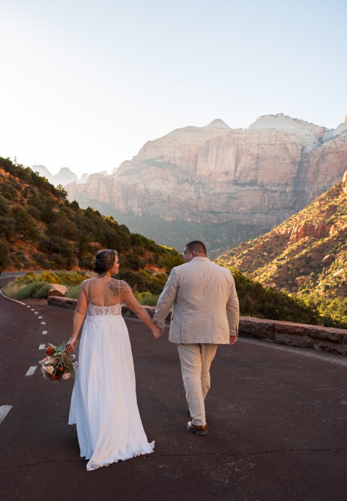 Bride and groom walking away from the camera holding hands in Zion National Park in Utah