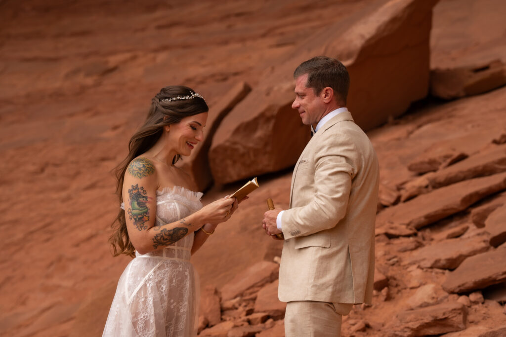 Bride reading her vows to the groom with red rock behind them in Moab, Utah