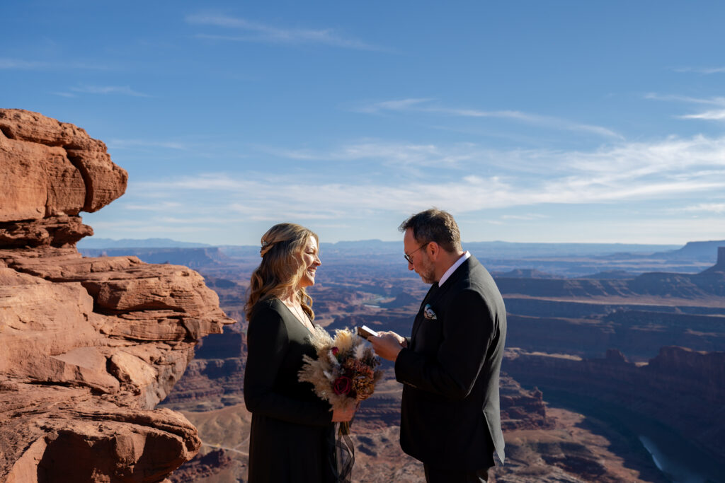 Groom reading his vows to the bride on the cliff of Dead Horse Point in Moab, Utah