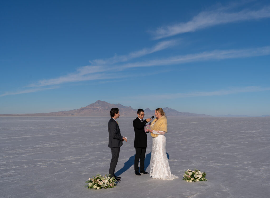 Officiant holding mic up to bride as she reads her vows to the groom at the Bonneville Salt Flats in Utah