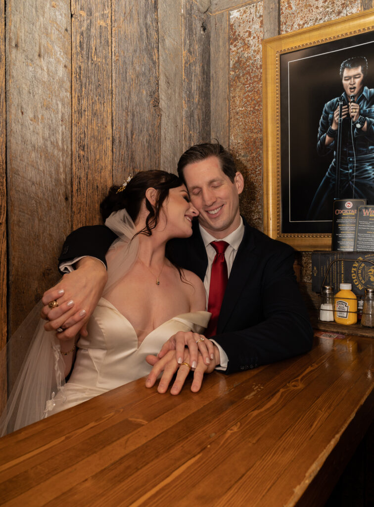 Bride and groom snuggling up to each other in a booth at a bar in Park City, Utah