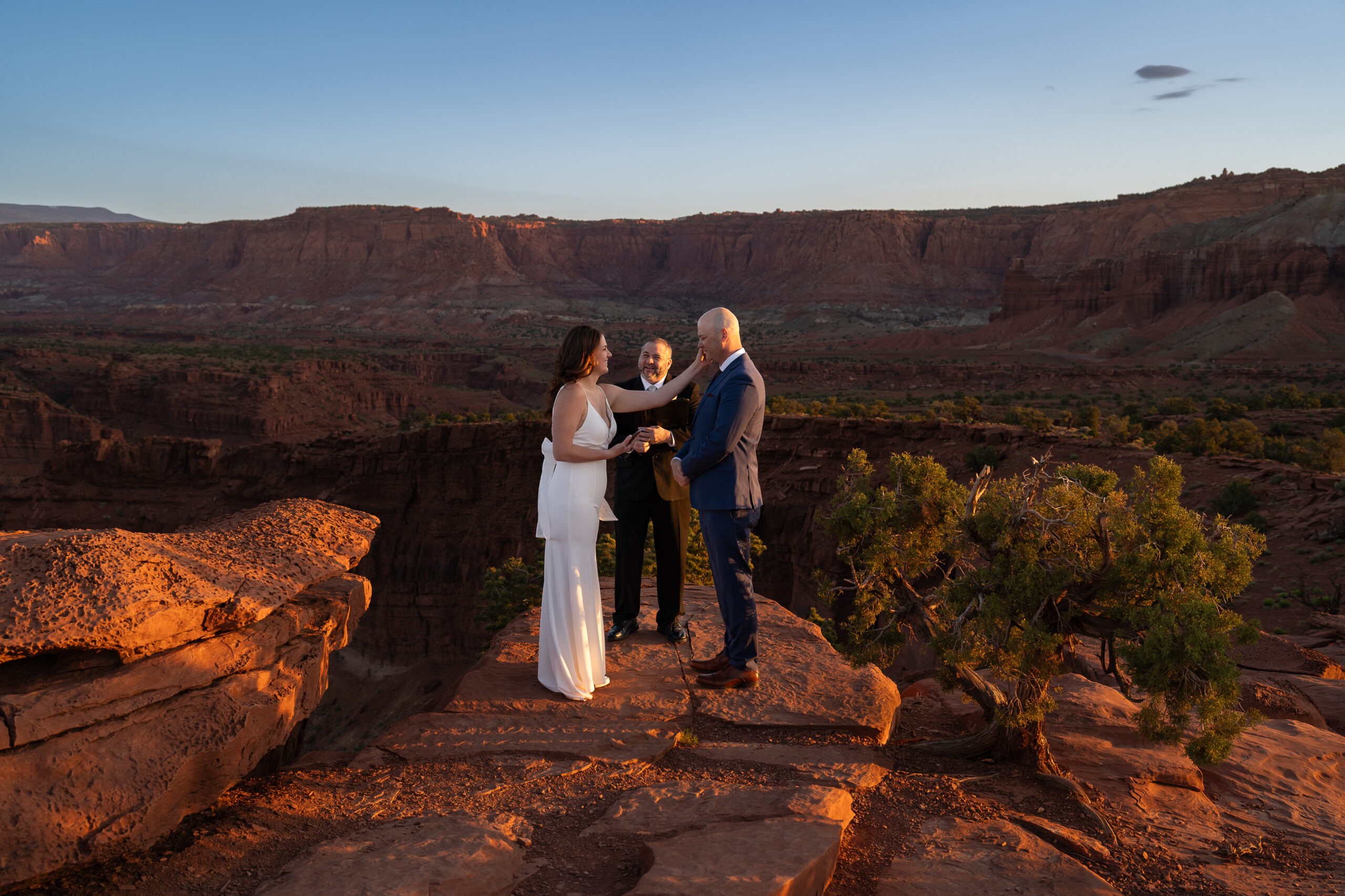 Bride wiping tears away from groom's face during their sunrise ceremony in Capitol Reef National Park in Utah.